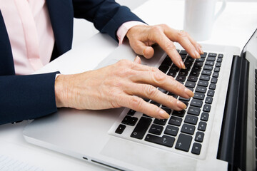 Cropped image of senior businesswoman typing on laptop