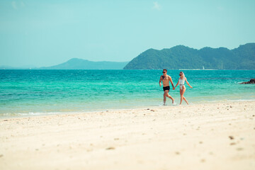 A romantic couple on the beach in a swimsuit, beautiful sexy young people. girl with  white dreadlocks and a man with a tattoo, having fun on the beach. Phuket. Thailand.