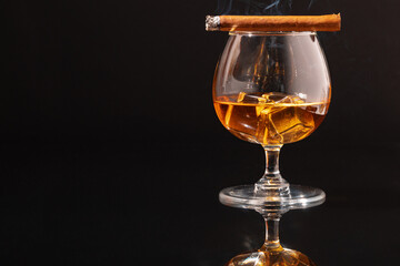 Obraz na płótnie Canvas Burning cigar and glass of whisky on black background