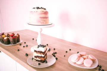Sponge cake with blueberries and different desserts on a wooden table