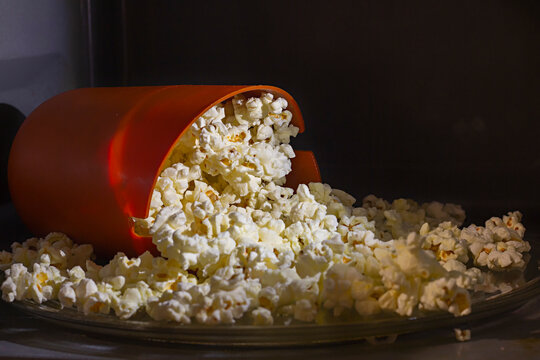 Orange Silicon Bucket Filled With Homemade Cooked Popcorn Inside A Microwave Oven. Special Silicon Bucket For Popcorn Microwave Cooking At Home. 