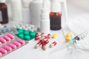 Heap of medical pills in white, red and other colors. Pills in plastic package with mask and needle. Concept of healthcare and medicine.