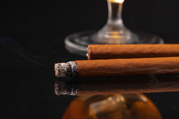 Burning cigar against black background close up