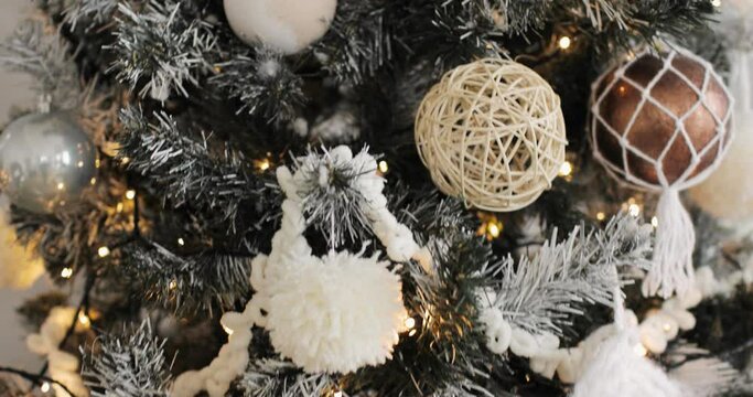 Happy New Year, Christmas, Xmas, holiday and celebration concept. Closeup of Christmas tree decorated with balls, garlands and pompons, camera in motion. Artificial fir tree with a white coating.