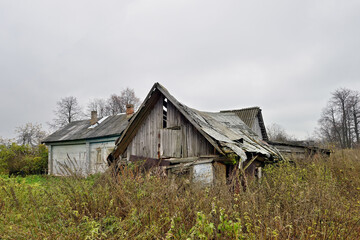 Ruined wooden farmhouse and barn. Abandoned village house. Concept: devastation, depression, decline of rural life