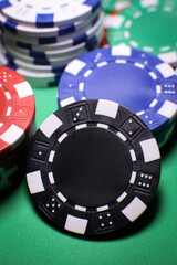 Different poker playing chips on a green table against black background. Online gaming. 