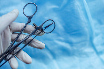 surgical instruments clamps and tweezers in the surgeon's hand