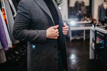 stylish man trying on a winter coat in a clothing store.
