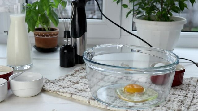 Woman hands prepares liquid dough. Break raw eggs into a glass bowl. Сlose up, cameras motion