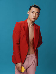 Fashionable man in a red jacket with a mobile phone in his hand pink pants blue background cropped view close-up