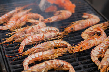 Process of cooking fresh red langoustine shrimps, prawns on grill at summer local food market - close up. Outdoor cooking, barbecue, gastronomy, seafood, cookery, street food concept
