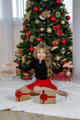 A beautiful little girl stands before the choice of a small or large gift for the New Year and Christmas. The girl decides which gift to choose