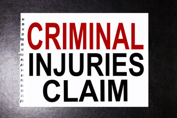 Naklejka premium CRIMINAL INJURIES CLAIM. text on white paper on black background
