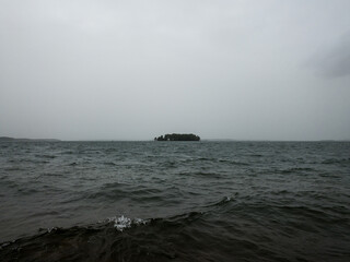 A small island which is out in the middle of a sea with a cloudy sky and a gloomy look