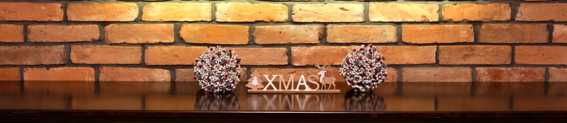 Fototapeta premium Xmas inscription and Christmas decorations on the background of an old brick wall.