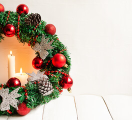 burning candles and christmas wreath with red balls and pine cones with copy space