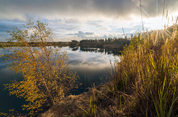 Autumn landscape with lake and clouds at sunset.