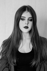 Portrait of a young girl with long hair. Black and white shooting at home. A woman stands on a white background.