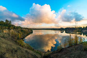 Large clouds at sunset over the lake in autumn .