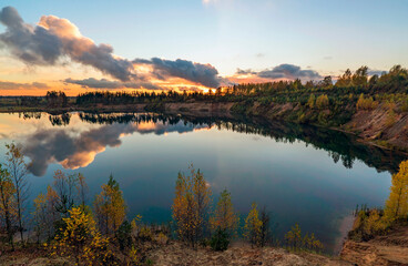 Naklejka na ściany i meble Autumn landscape with beautiful clouds over the lake at sunset.