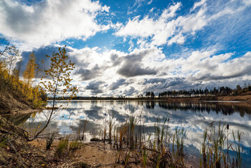 Autumn landscape with beautiful clouds over the lake with a mirror image.