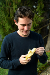 Young man peeling a banana and eating it