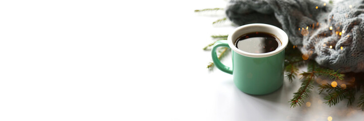 Horizontal light banner with greenery ceramic coffee cup on the knitted grey scarf and fir branches background. Cozy vibes concept