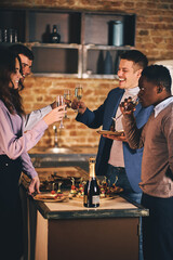 Happy friends clinking flutes with sparkling wine