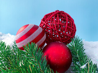 Close up red christmas balls on pine tree branches on snowy background.