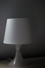 A white bedside lamp with side lighting