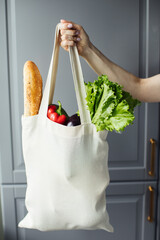 Female hand with eco bag on grey background