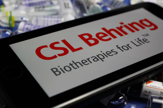 Viersen, Germany - May 9. 2020: Close up of mobile phone screen with logo lettering of CSL Behring biotherapies pharmaceutical company on pile drug ampules