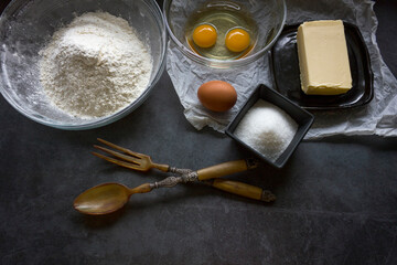 Ingredients for preparing butter cookies on black kitchen table. Flat lay.