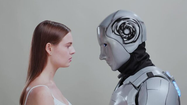 Beautiful woman and robotic silver cyborg looking at each other isolated on background. Human interaction with AI. Futuristic concept.