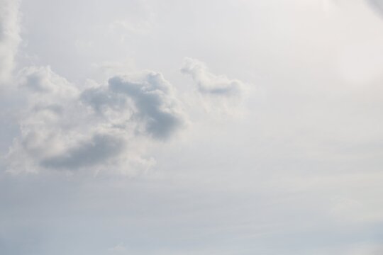 Gray fluffy cloud on a pale grey sky background