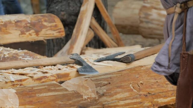 Man lumberjack cutting large log with axe - wood shavings, chips flying at summer historical medival festival - close up, slow motion. Craftsmanship, revival, reenactment, handwork concept