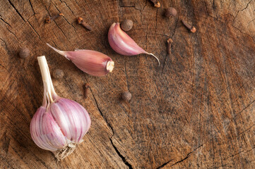 garlic, garlic cloves, allspice and cloves on an old wooden background