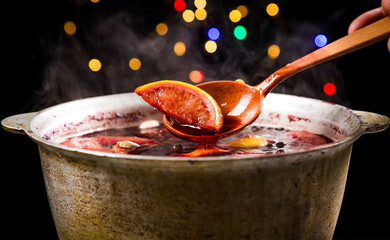 Big kettle pot of traditional hot steaming Christmas drink mulled red spiced wine boiling with...