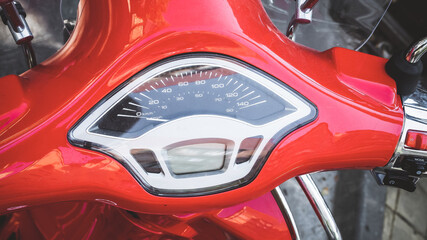 Speedometer on the handlebar of a glossy red motorcycle. Closeup photo