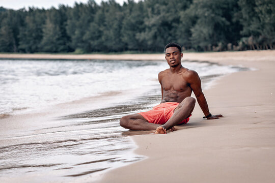  afro american young man relaxing on beach. Muscular guy wearing red shorts.  Shirtless male model sunbathing. Shirtless male model sunbathing. Swaggy C on the beach. Phuket.