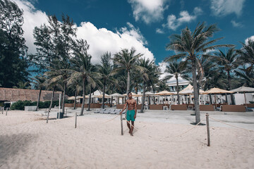 Fashion photo of african american athletic man with sport body posing near the hotel and palm trees. Phuket. Thailand.