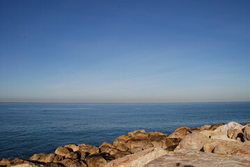 Sea view from a stone breakwater.
Mediterranean Sea, sunny day. Breakwater stones close up. Blue surface of sea water and white blue sky over the sea.