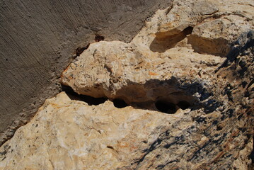 Textured stones under the slate light.
Textured stones are yellow-brown. The sun-baked nervousness cast a shadow on the stones. Part of the stone has an even cut.
