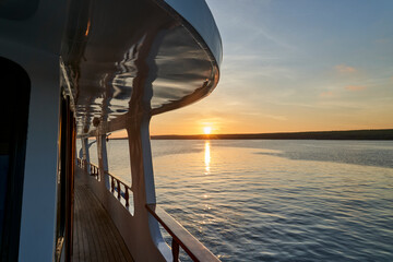 beautiful and spectacular sunset over a motor yacht with reflections on the white paint and details of the vessel, lying in the graet darwin bay of genovesa island, galapagos islands, Ecuador