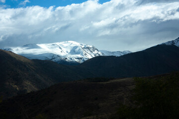 in Andes Merry Christmas and Chilean mountains between clouds and mounds of earth the white snow under the sun