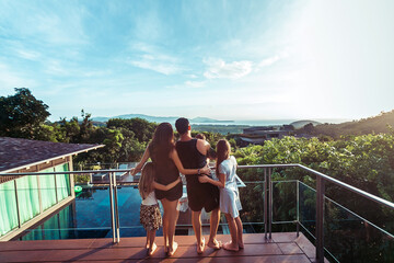 Family in the terrace by the sea, watching the sunset. Back view. Phuket. Thailand