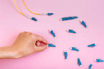 Hand takes blue LC optical attenuator on pink background