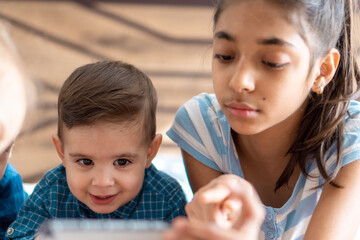 friendship, childhood, technology concepts - 2 young children baby of different nationalities Persian and Slavic appearance watch cartoon on smartphone on bed. kids preschool speak by video conference