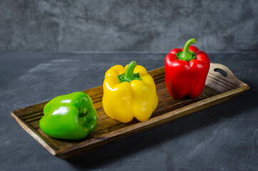 Red, yellow and green bell pepper paprika on a grey background