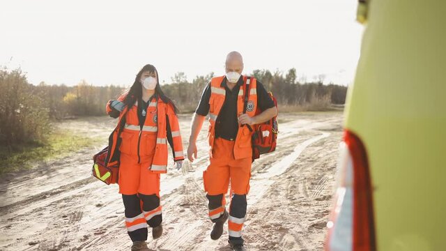 Two paramedics in full equipment walking towards ambulance vehicle